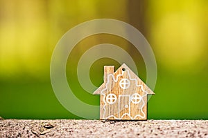 Close-up of wooden house model on green forest background. Eco-friendly house and sustainability concept. World