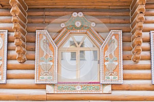 Close up of wooden house - open window with carved colorful shutters. Traditional russian terem