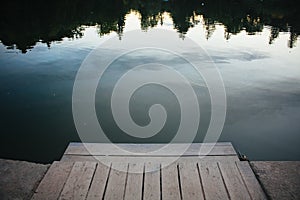 Close up wooden lake dock in front of woods reflecting in water concept photo