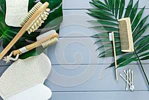 Close up Wooden massage brushes for skin and body care and monstera tropic leaf on gray background. Beauty, spa and bath