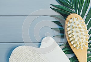 Close up Wooden massage brushes for skin and body care and monstera tropic leaf on gray background. Beauty, spa and bath