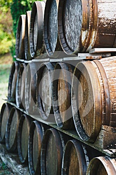 Close up of wooden old wine barrels stacked outside of a winery on vineyard