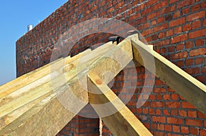 Close up on wooden rafters, eaves, wooden beams installed on brick wall with bitumen waterproofing membrane and metal anchors atta