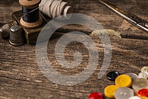 Close-up of wooden sewing spool and buttons set on wooden table