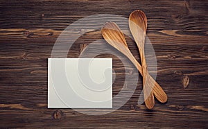 Close up wooden spoons, and blank paper on wooden board.