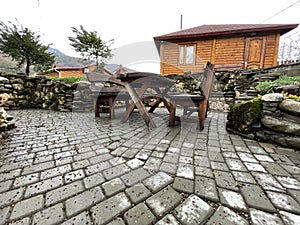 Close up of wooden table with benches in countryside. Log table and benches in empty village in cloudy weather.