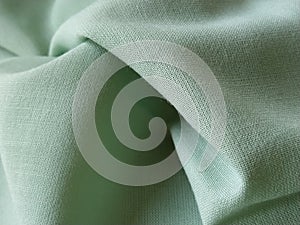 Close up of a woolen fabric of green color. Abstract canvas background, empty template. Thin natural fabric, wool or linen