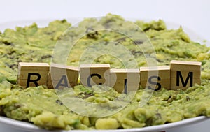 Close up of  word racism spelled by wooden letters on disgusting green slimy stodge focus on word center