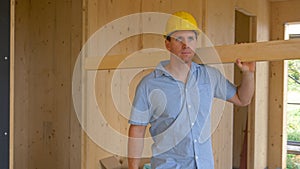 CLOSE UP: Worker carrying a long plank looks around the beautiful CLT house.