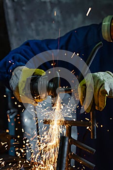 Close-up of worker cutting metal with grinder. Sparks while grinding iron.