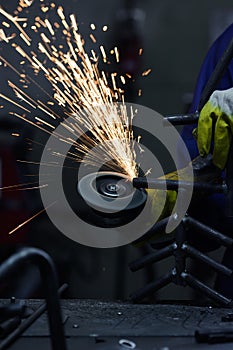 Close-up of worker cutting metal with grinder. Sparks while grinding iron.