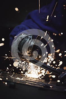 Close-up of worker cutting metal with grinder. Sparks while grinding iron. Low depth of field.