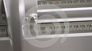 Close-up of worker of furniture factory measuring a wooden block with industrial measuring device. Action. Production