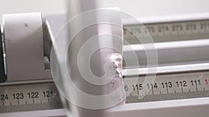 Close-up of worker of furniture factory measuring a wooden block with industrial measuring device. Action. Production