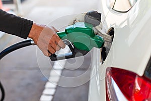 close up worker hand holding nozzle fuel fill oil into car tank at pump gas station