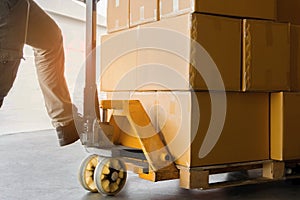 Close up worker with hand pallet truck and package boxes on pallet