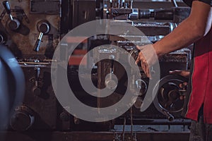 Close-up Worker handles metal at lathe operating lathe grinding machine in uniform with safety - metalworking industry concept.