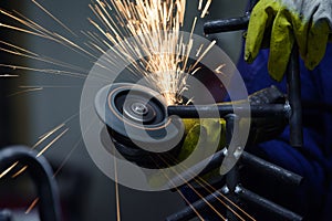 Close up of worker hands grinding a piece of welded pipe