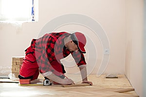 Close up of worker installing wood parquet. Worker laying parquet flooring. Worker installing wooden laminate flooring