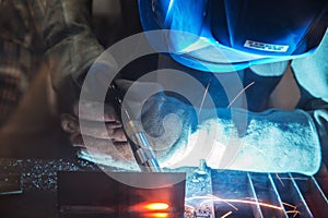 Close up of worker with protective mask welding metal.Selective