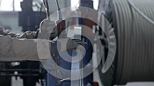 A close-up of the worker's hand is pressed by the electric lift button to move the bobbin with metal tape