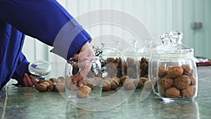 Close-up, worker s hands put walnuts in glass jars. different kinds, grown selectively, hybrids of walnuts of better