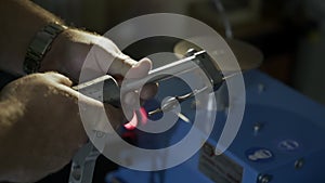 Close-up, worker sharpens nail scissors on a grindstone, slow-motion low light scene.