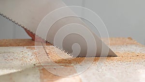 Close up of the worker uses a handsaw and saws a wooden shield at home. Construction concept