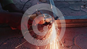 Close up of a workers hand using an angle grinder on metal with sparks flying