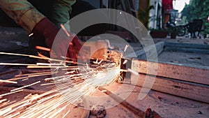 Close up of a workers hand using an angle grinder on metal with sparks flying