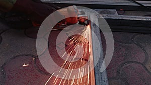 Close up of a workers hand using an angle grinder on metal with sparks flying