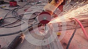 Close up of a workers hand using an angle grinder on metal with sparks flying