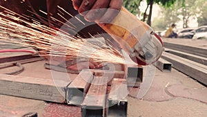 Close up of a workers hand using an angle grinder on metal with sparks flying