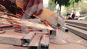 Close up of a workers hand using an angle grinder on metal with sparks flying