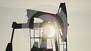 Close-up of working oil pump in the background of the sun