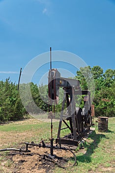 Working pump jack pumping crude oil at oil drilling site in rural USA