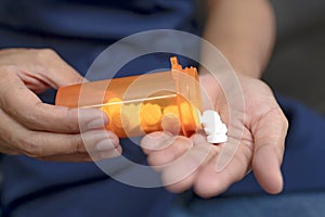 Close up of working woman taking in pill she is pours the pills out of the bottle,taking painkiller to reduce sharp ache concept,