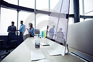 Close-up of workplace in modern office with business people behind. Colleagues meeting to discuss their future financial