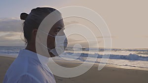 Close up worried man wearing medical mask on the beach at sunrise