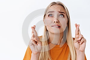 Close-up worried, very nervous blond caucasian woman in orange t-shirt, fingers crossed hope god hear prayers as furrow