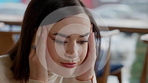 Close-up of worried young Caucasian woman holding head in hands thinking. Headshot portrait of stressed businesswoman