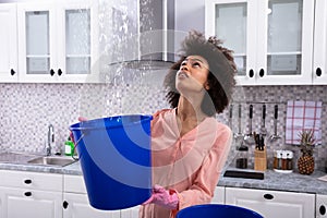 Woman Collecting Water Leaking From Ceiling In Bucket