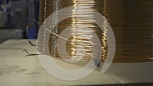 Close-up of wound copper wire in production. Creative. Thin line of wire on industrial coil. Production of copper wire