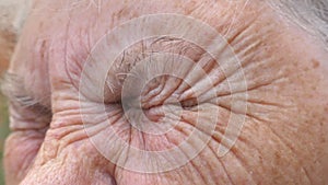 Close up wrinkled face of old grandmother looking into the distance with a sad sight. Portrait of mature woman strongly