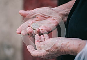 Close-up wrinkled hands of an elderly woman counting coins