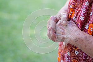 Close-up of wrinkled hands senior woman while standing in a garden. Hope, Faith. Concept of aged people and religion