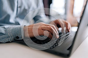 Close-up wrinkly hands of unrecognizable senior older businessman typing on laptop keyboard. Closeup cropped shot of