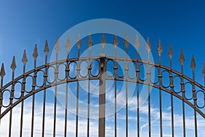 Wrought Iron Gate with Sharp Points on Blue Sky with Clouds