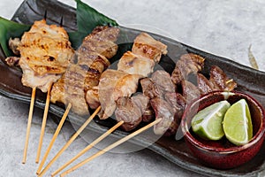 Close-up Yakitori Japanese-Style Grilled Chicken Skewers with chicken and internal organ served with sliced lime.