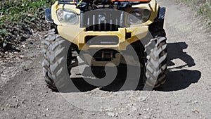 Close-up of a yellow ATV riding on a forest dirt road. Front view, shooting in motion. Hiking on a quad bike. Slow